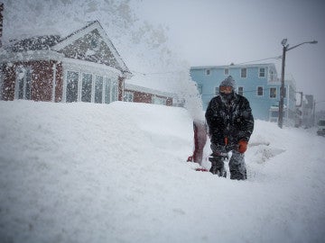 Un hombre retirando nieve frente a su casa