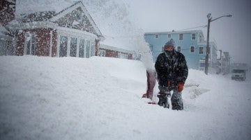 Un hombre retirando nieve frente a su casa