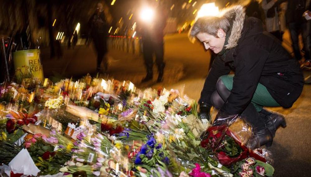 Una mujer deja flores en el lugar donde se produjeron los tiroteos en Copenhague.