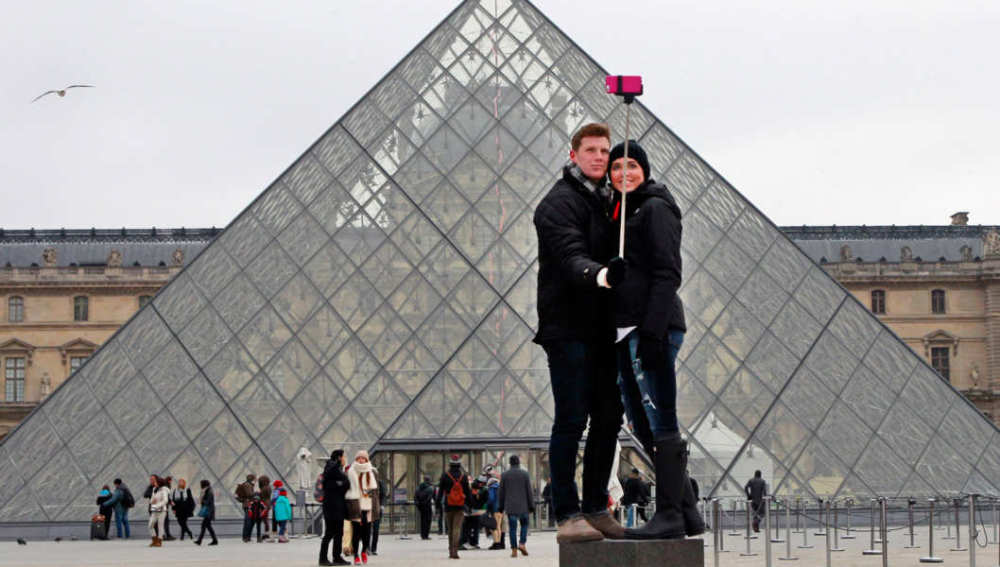 Pareja usando un palo de selfi en el Louvre