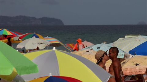 Dos ba&ntilde;istas entre sombrillas en una playa.