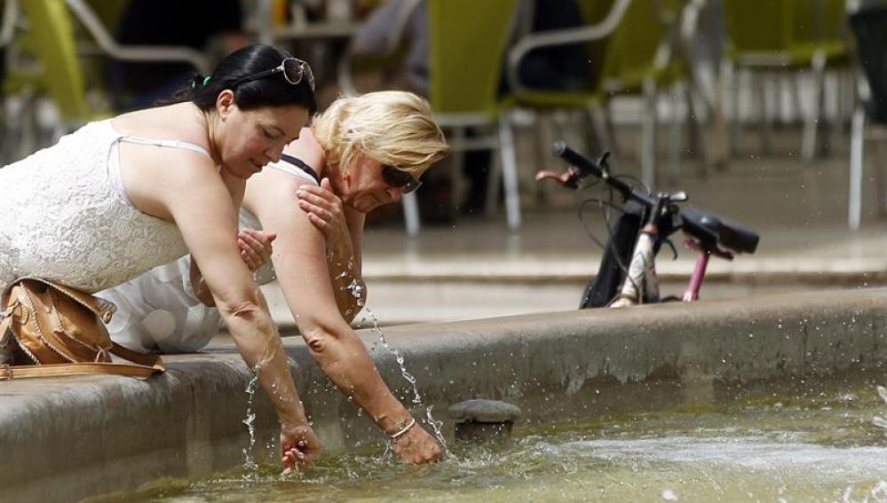 Dos mujeres se refrescan en una fuente
