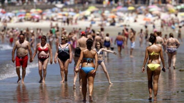 Varios bañistas pasean por una playa de Galicia