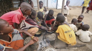 Niños marfileños comen en el campamento de refugiados de Bahn