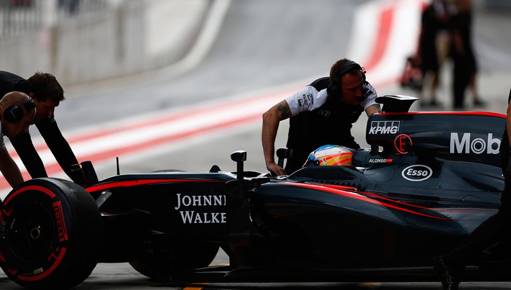 Los mecánicos del McLaren empujan el monoplaza de Alonso dentro del box