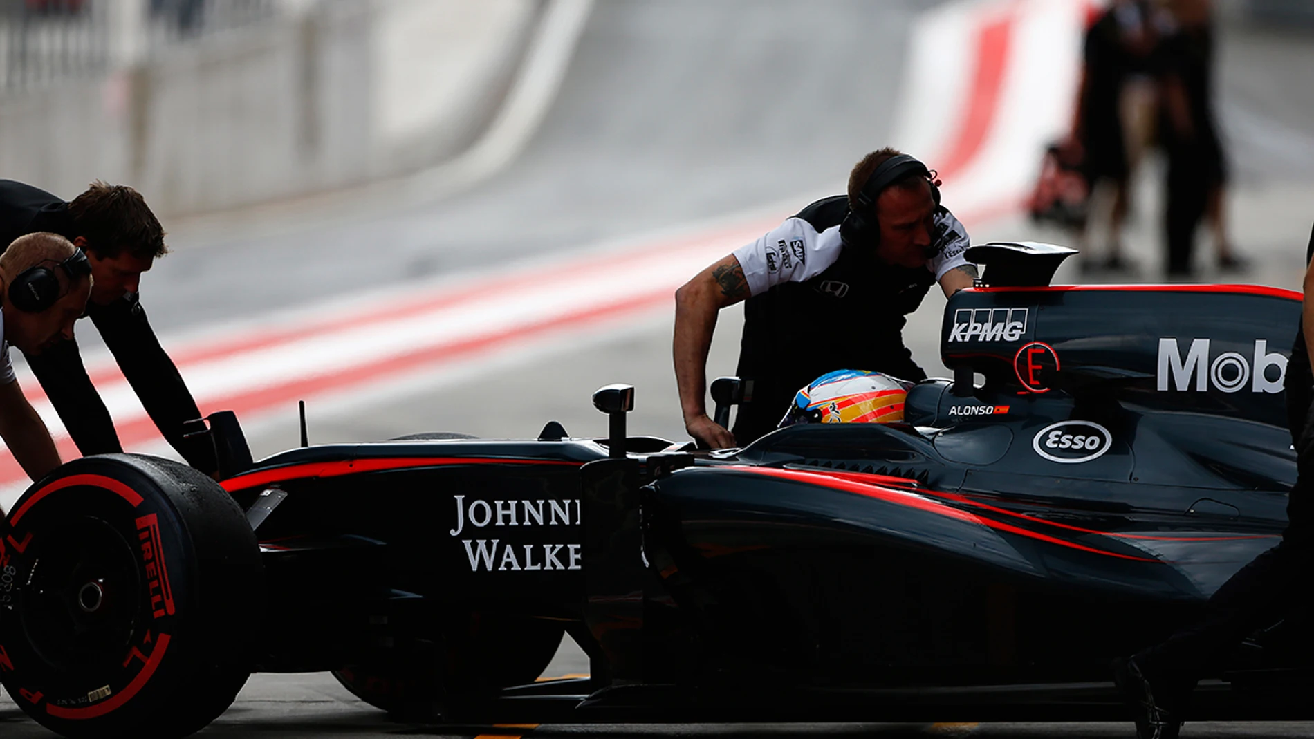Los mecánicos del McLaren empujan el monoplaza de Alonso dentro del box