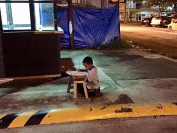 Niño estudiando a la luz de un McDonald's