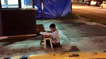 Niño estudiando a la luz de un McDonald's