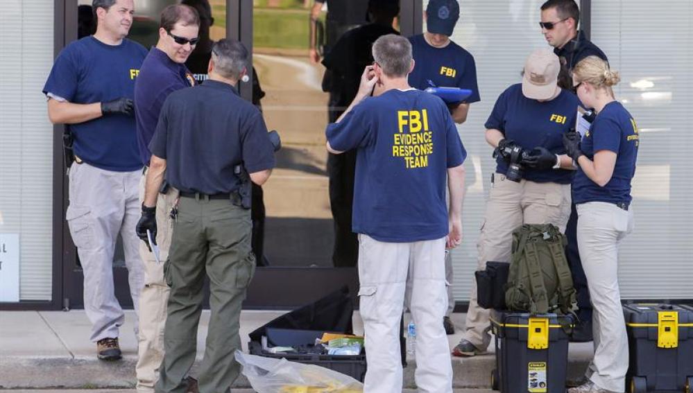 Miembros del equipo de Reacción de Evidencias del FBI permanece afuera del edificio de reclutamiento militar de EE.UU.