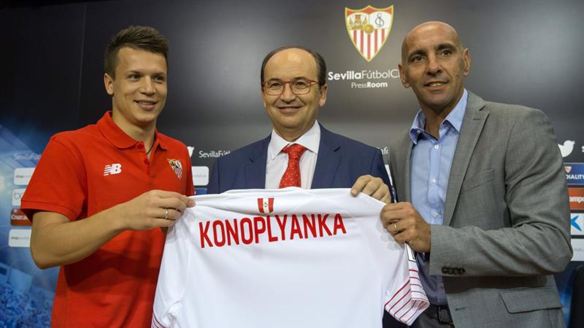 Monchi ayuda a sostener la camiseta de Konoplyanka, un nuevo refuerzo del Sevilla