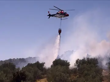 Un avion contra incendios hace una descarga sobre el fuego Un avion contra incendios hace una descarga sobre el fuego