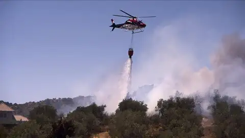 Un avion contra incendios hace una descarga sobre el fuego Un avion contra incendios hace una descarga sobre el fuego