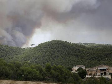 Un helicóptero trabaja cerca de varias viviendas para combatir el incendio