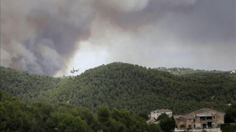 Un helic&oacute;ptero trabaja cerca de varias viviendas para combatir el incendio