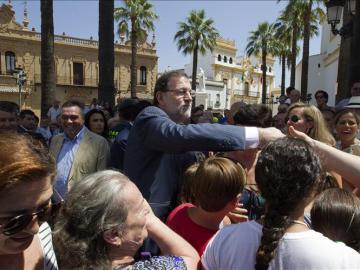 El presidente del Gobierno y del Partido Popular, Mariano Rajoy (c), saluda a varios vecinos de La Palma del Condado (Huelva),