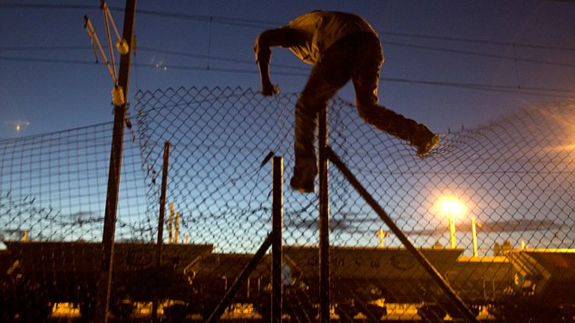 Inmigrante saltando una verja del Eurotunnel Inmigrante saltando una verja del Eurotunnel