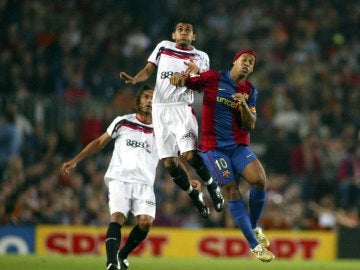 Alves y Ronaldinho luchan por un balón