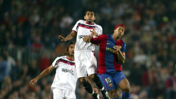 Alves y Ronaldinho luchan por un balón