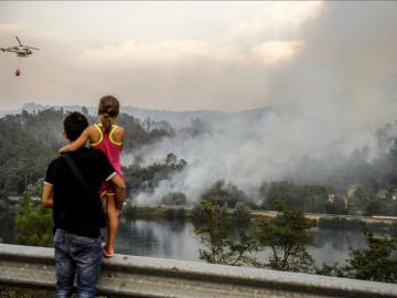 Un helicoptero realiza trabajos de extinción sobre las llamas del incendio declarado el domingo, en el termino municipal orensano de Pereiro de Aguiar.