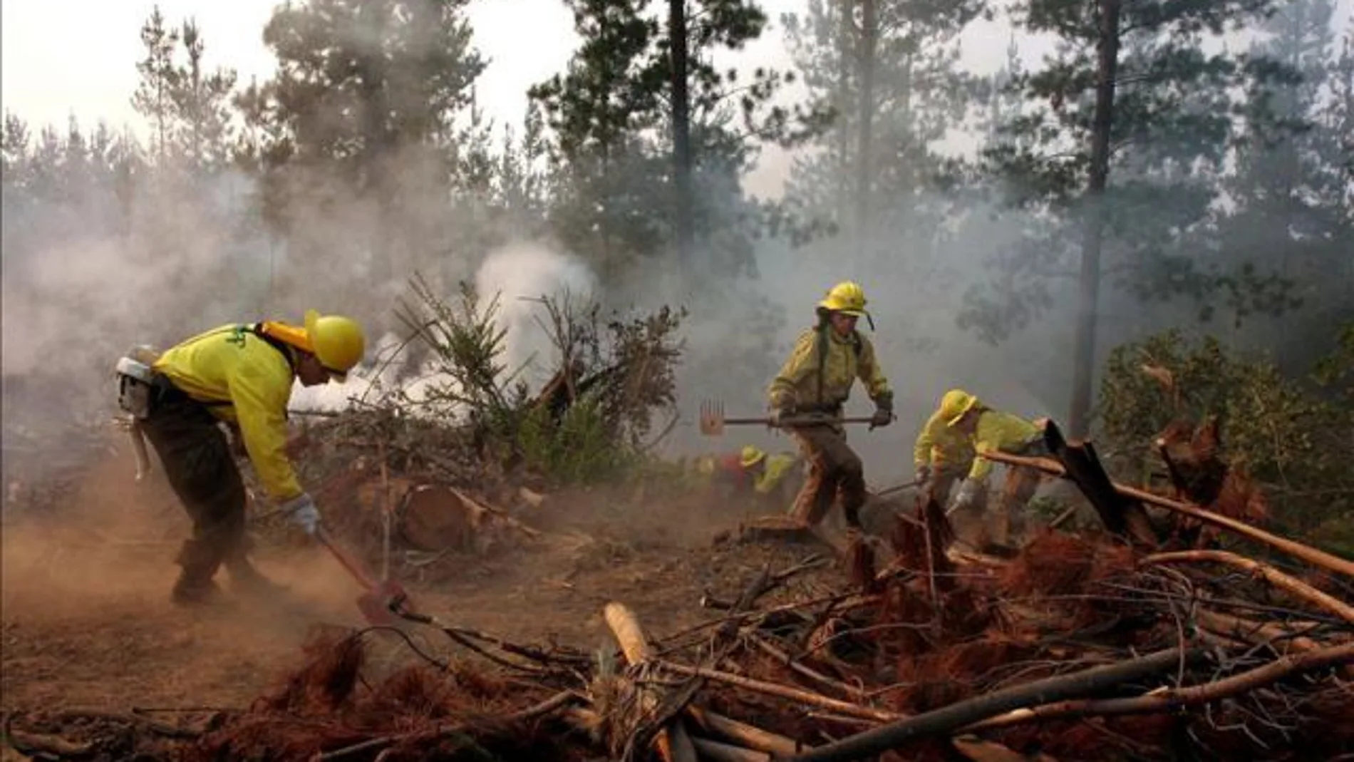 Un grupo de bomberos apagan un incendio Un grupo de bomberos apagan un incendio