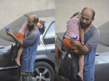 El padre junto a su hija en brazos vendiendo bolígrafos en la calle.