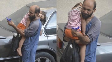 El padre junto a su hija en brazos vendiendo bolígrafos en la calle.