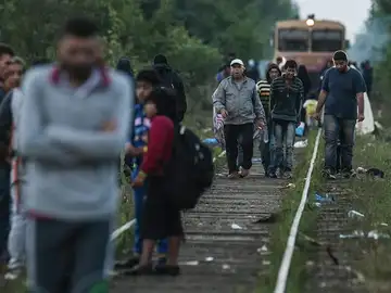 Inmigrantes caminan sobre las vías de un tren en la frontera entre Hungría y Serbia Inmigrantes caminan sobre las vías de un tren en la frontera entre Hungría y Serbia