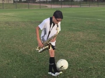 Un niño toca el saxo mientras domina el balón