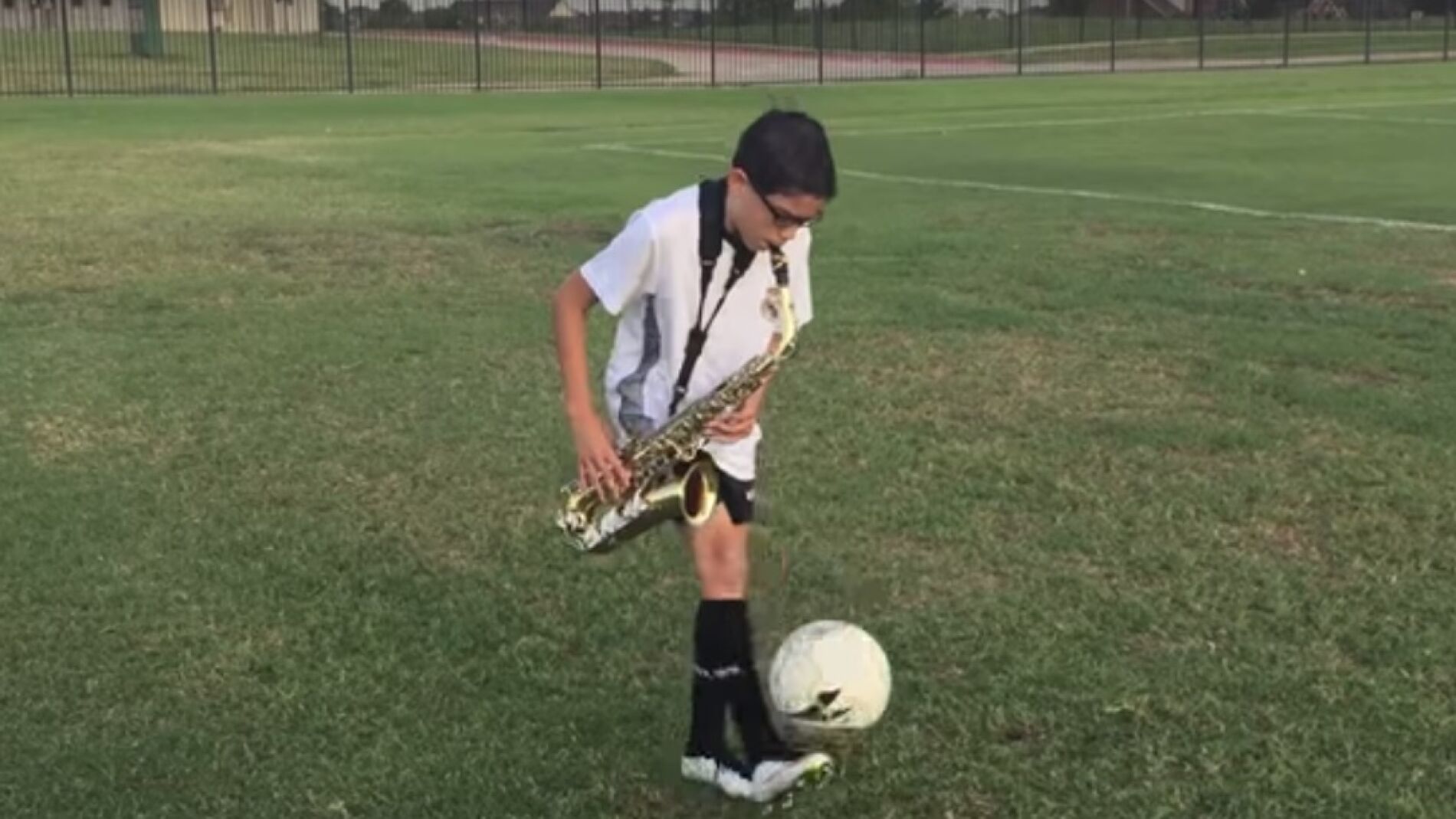 Un ni&ntilde;o toca el saxo mientras domina el bal&oacute;n