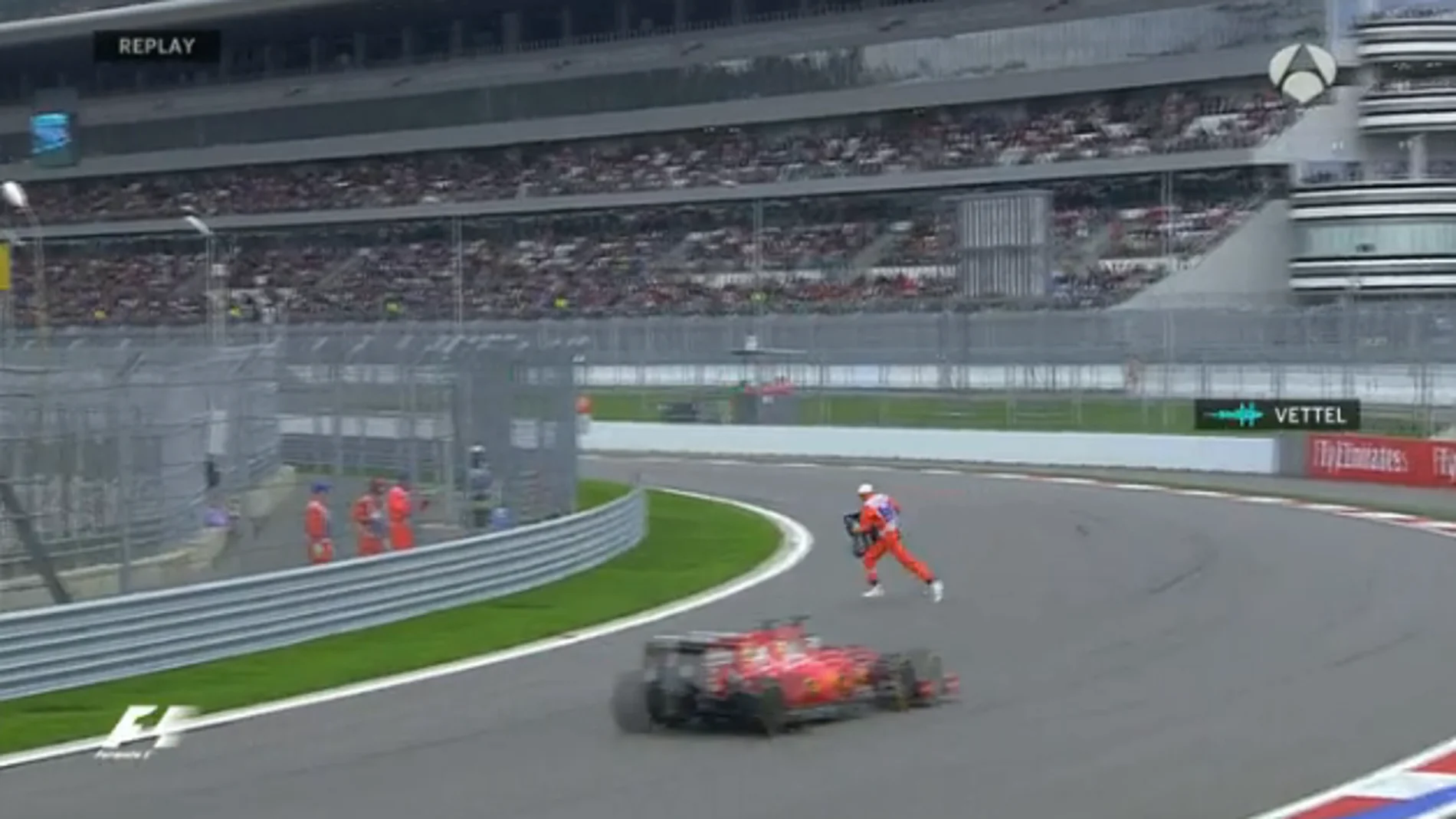 Un comisario retira la pieza del alerón de Carlos Sainz con Vettel justo detrás