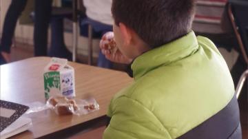 Un niño come solo en el colegio