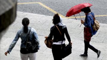 Paseantes tratan de cubrirse de las fuertes lluvias con paraguas
