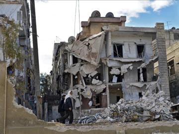 Varios civiles pasando por un edificio destruído por los bombardeos en Alepo, Siria.