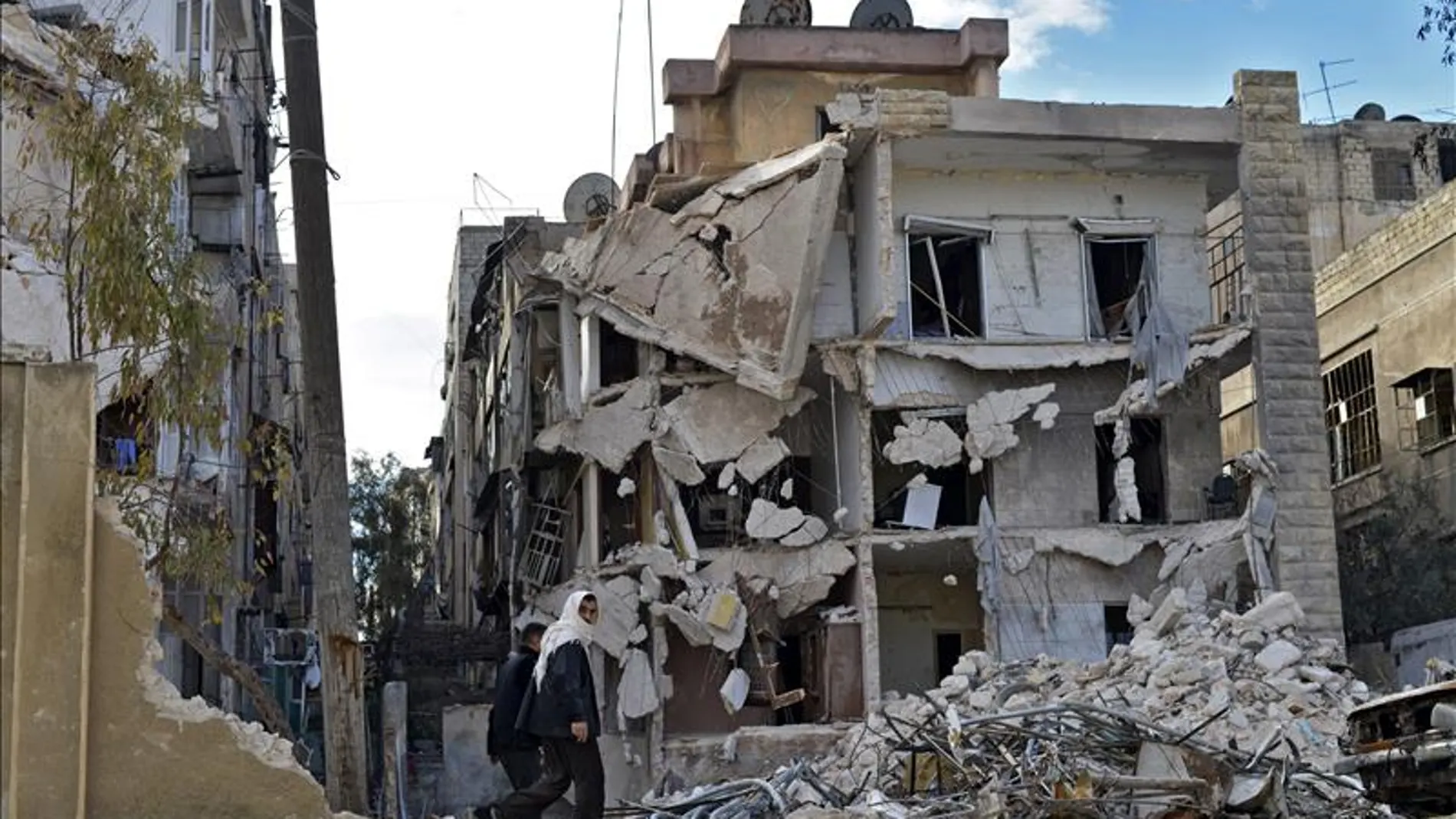 Varios civiles pasando por un edificio destruído por los bombardeos en Alepo, Siria. Varios civiles pasando por un edificio destruído por los bombardeos en Alepo, Siria.