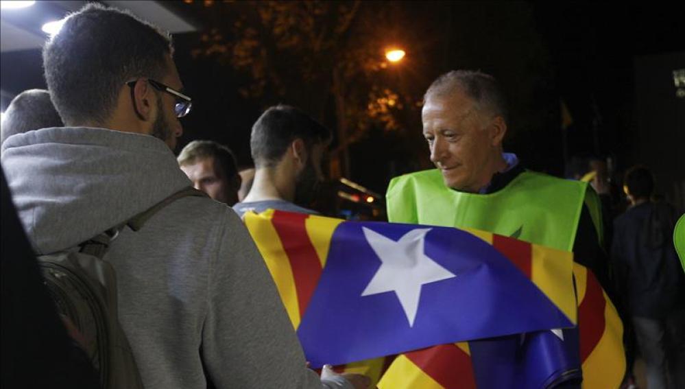 Un voluntario reparte banderas independentistas a la afición en los exteriores del Camp Nou