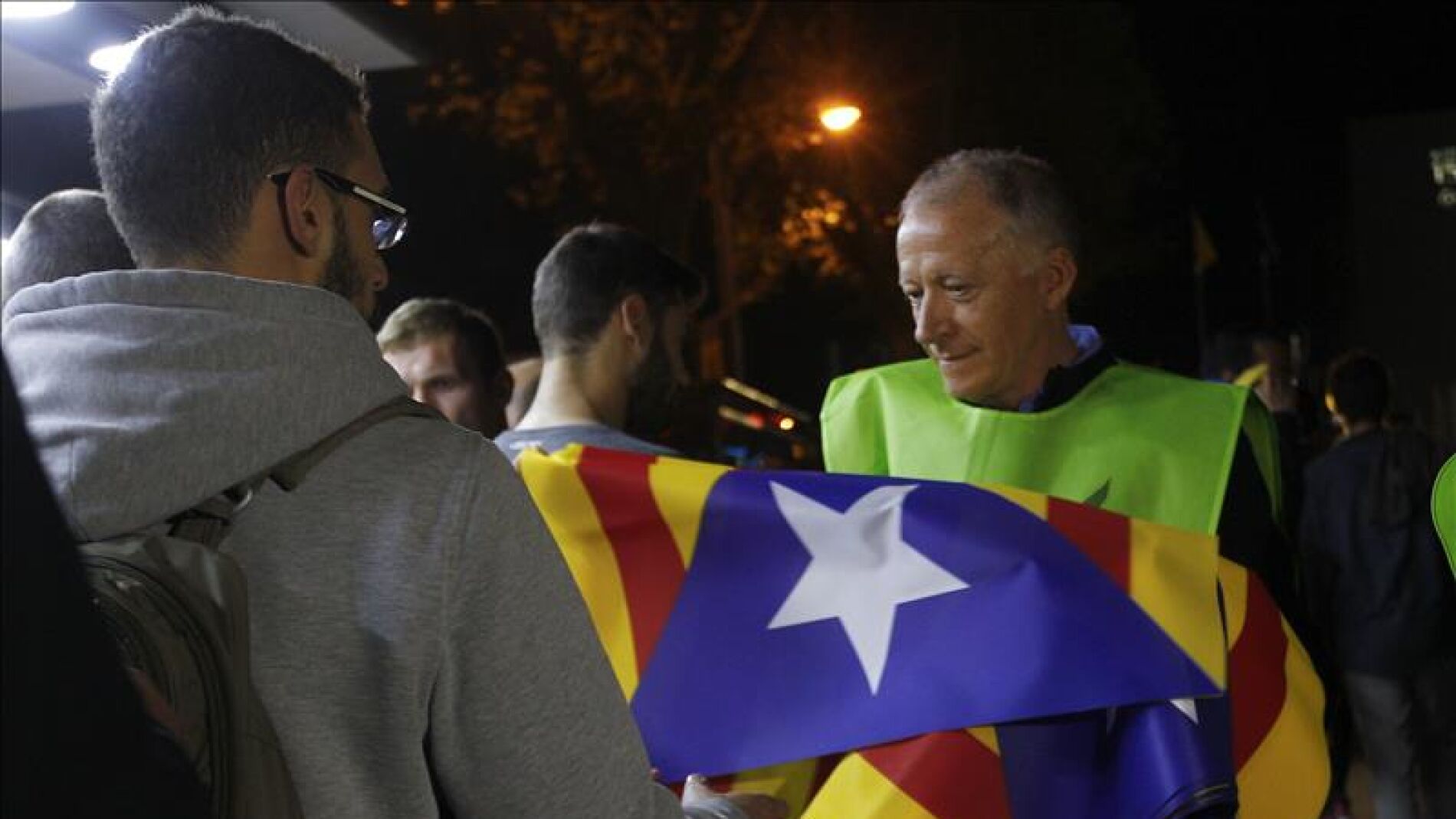 Un voluntario reparte banderas independentistas a la afici&oacute;n en los exteriores del Camp Nou