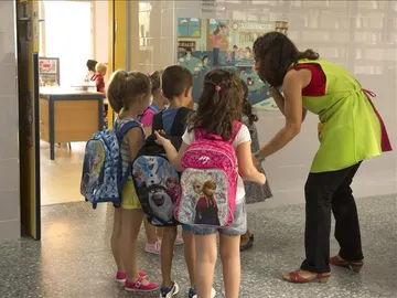 Varios niños entran al colegio con su profesora Varios niños entran al colegio con su profesora