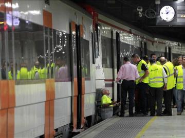 Trabajadores de RENFE revisan un tren en un andén de una estación en Barcelona.