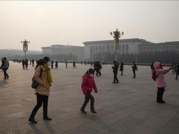 Los viandantes usan máscaras protectoras mientras recorren la plaza de Tiananmen en Beijing, China