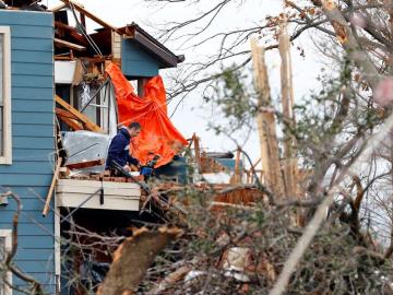 Un hombre recoge sus pertenencias en una casa destrozada