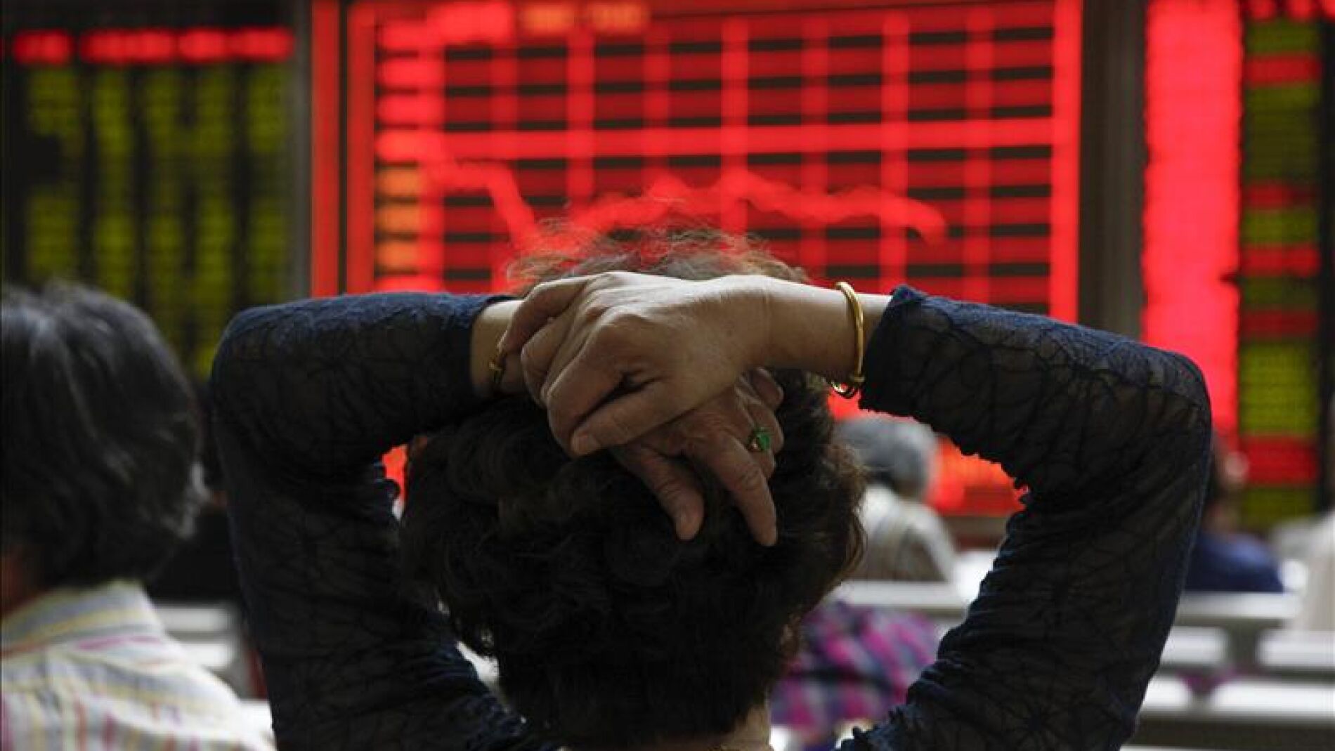 Una mujer comprueba la evoluci&oacute;n de la bolsa de Shang&aacute;i (China)