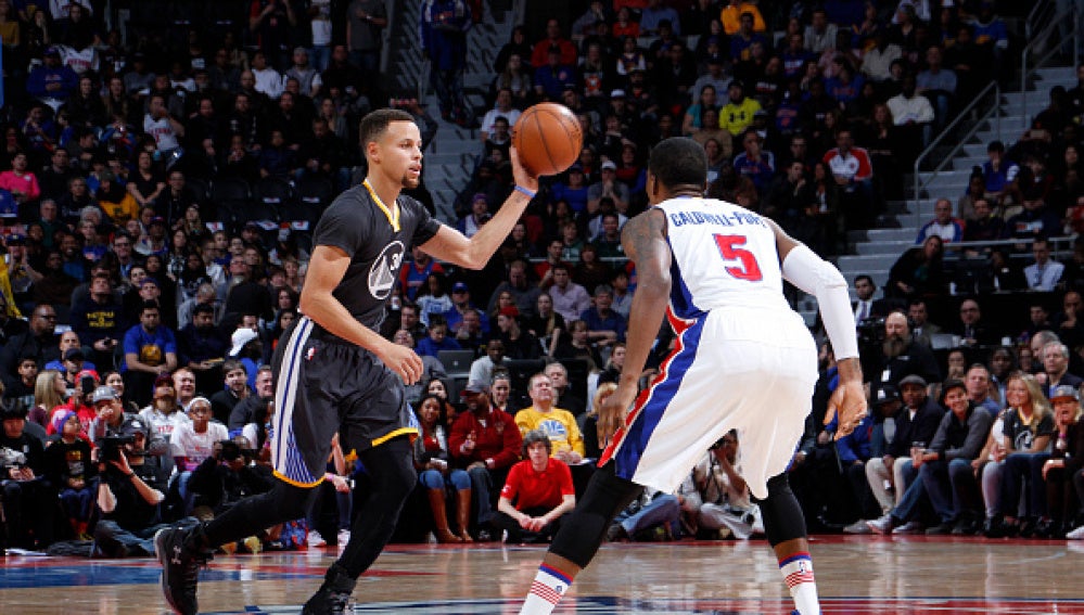 Stephen Curry conduce el balón ante la defensa de Caldwell-Pope