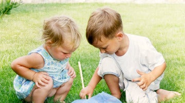 Imagen de dos niños jugando en el césped