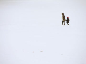 Una madre y su hijo caminan sobre la nieve