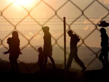 Varios inmigrantes caminan alrededor de una valla