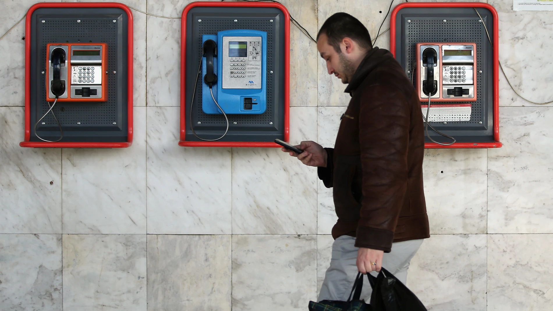 Un peatón camina mirando su teléfono móvil Un peatón camina mirando su teléfono móvil