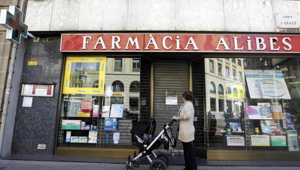 Una mujer contempla la fachada de una farmacia cerrada en el centro de Barcelona