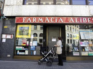 Una mujer contempla la fachada de una farmacia cerrada en el centro de Barcelona