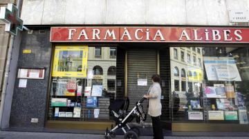 Una mujer contempla la fachada de una farmacia cerrada en el centro de Barcelona