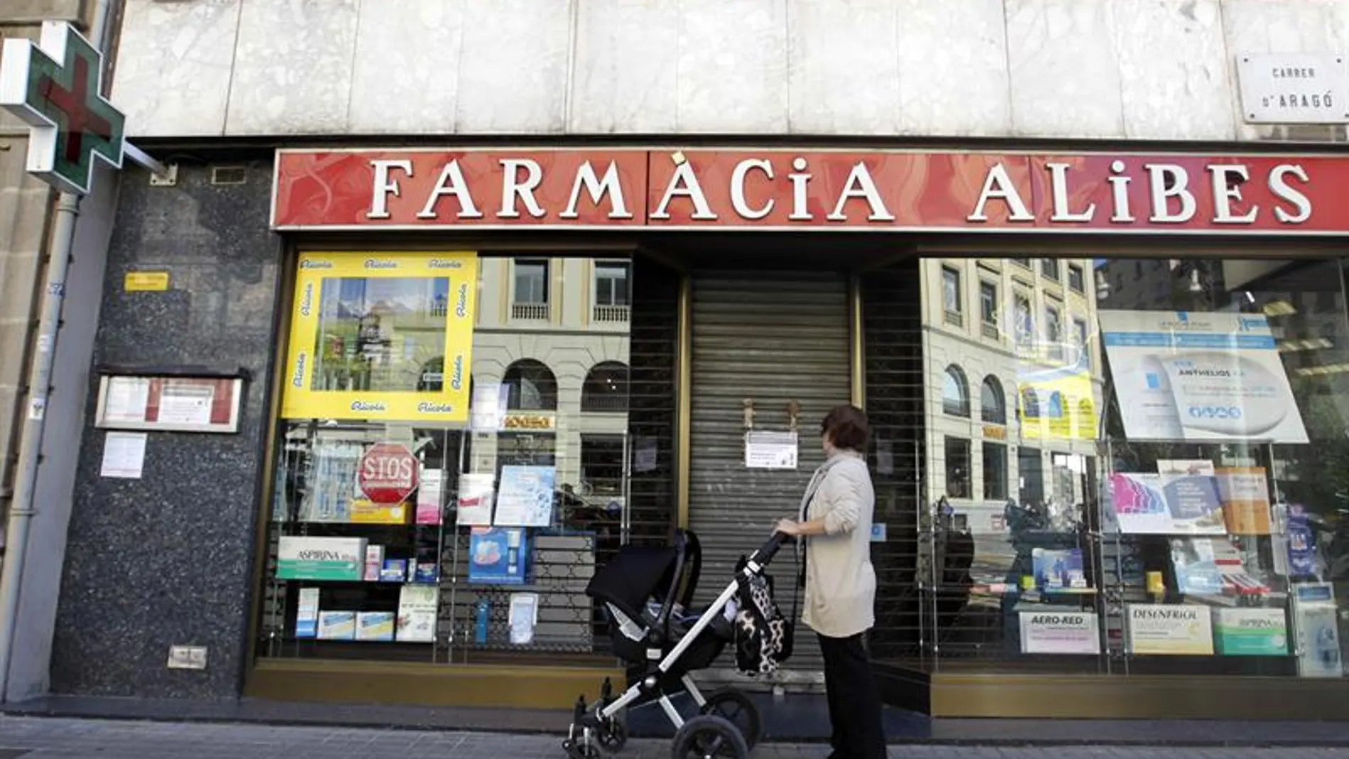 Una mujer contempla la fachada de una farmacia cerrada en el centro de Barcelona Una mujer contempla la fachada de una farmacia cerrada en el centro de Barcelona